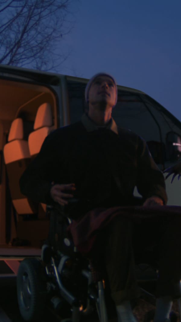 Eine Person im Rollstuhl wird über eine Rampe an der seitlichen Schiebetür beim Einstieg ins Fahrzeug unterstützt.